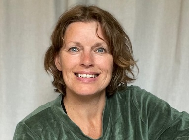 Woman smiling in green sweater.
