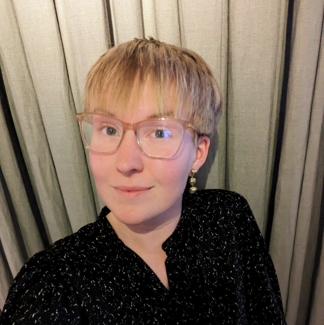 Close up photo of a woman with blond short hair and glasses.