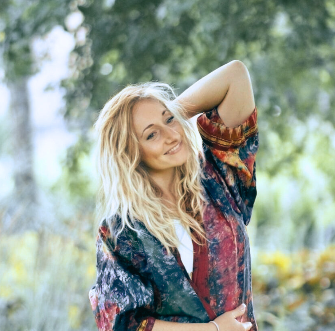 A blond woman smiling outdoors.